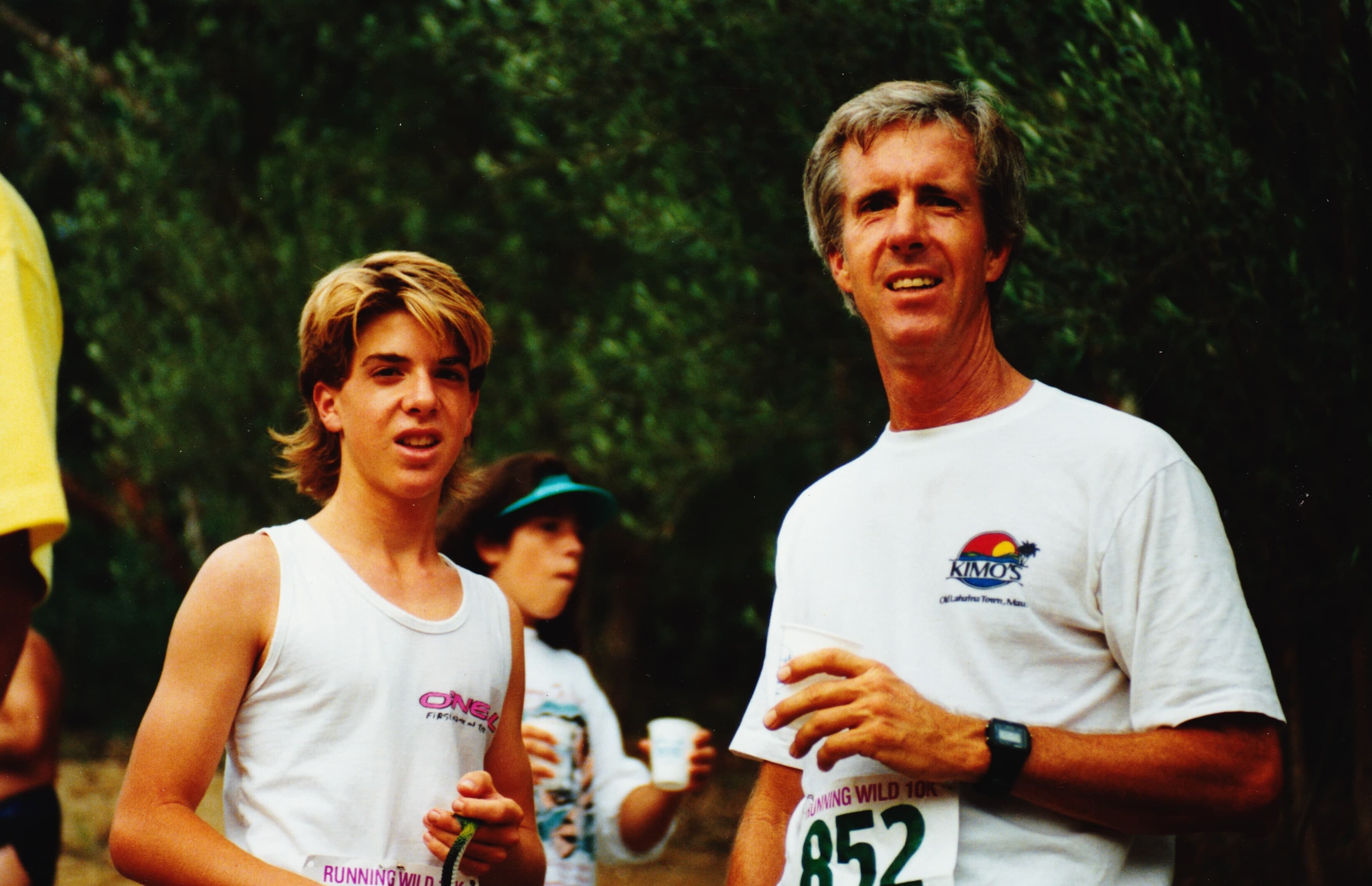 A teenage Rusty with their father at a Running Wild 10K, both wearing race bibs.